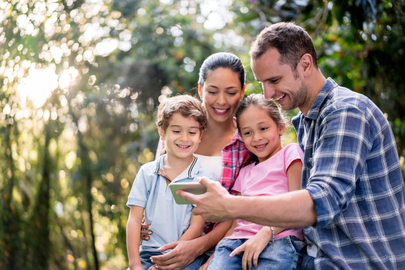 Happy family social networking outdoors using a cell phone