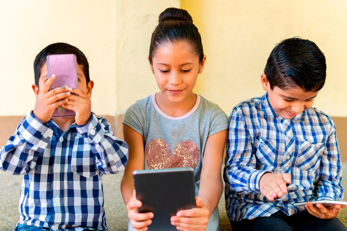 three child brothers on cell phone and tablet