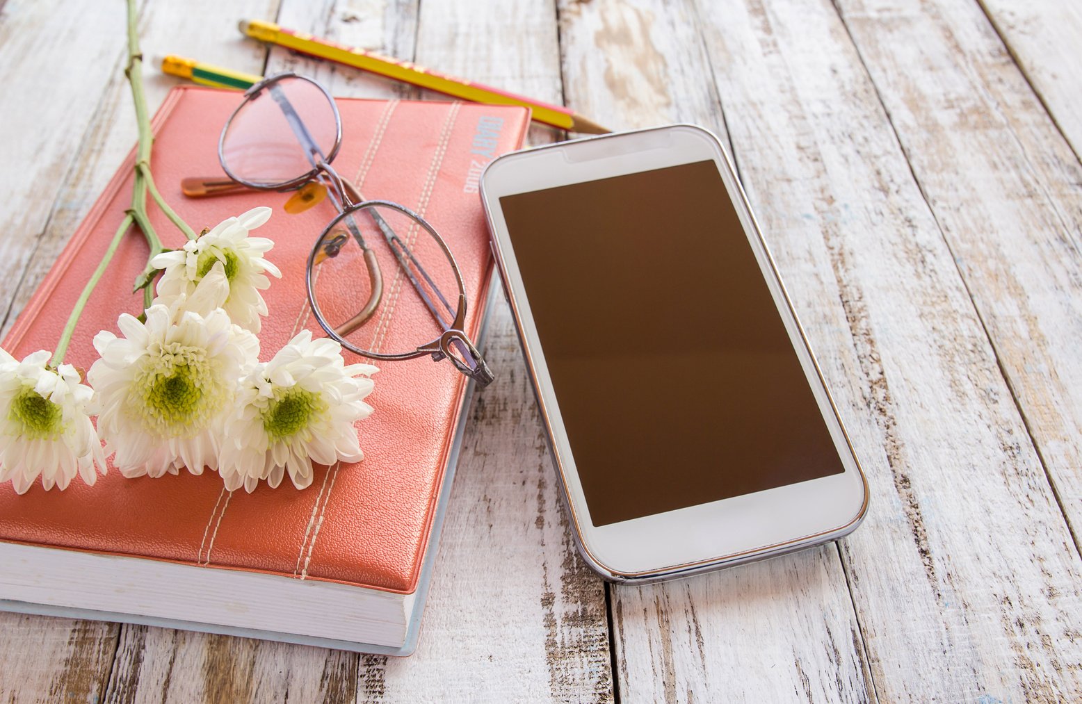 White Flower and Pencil on Notebook with Smartphone 