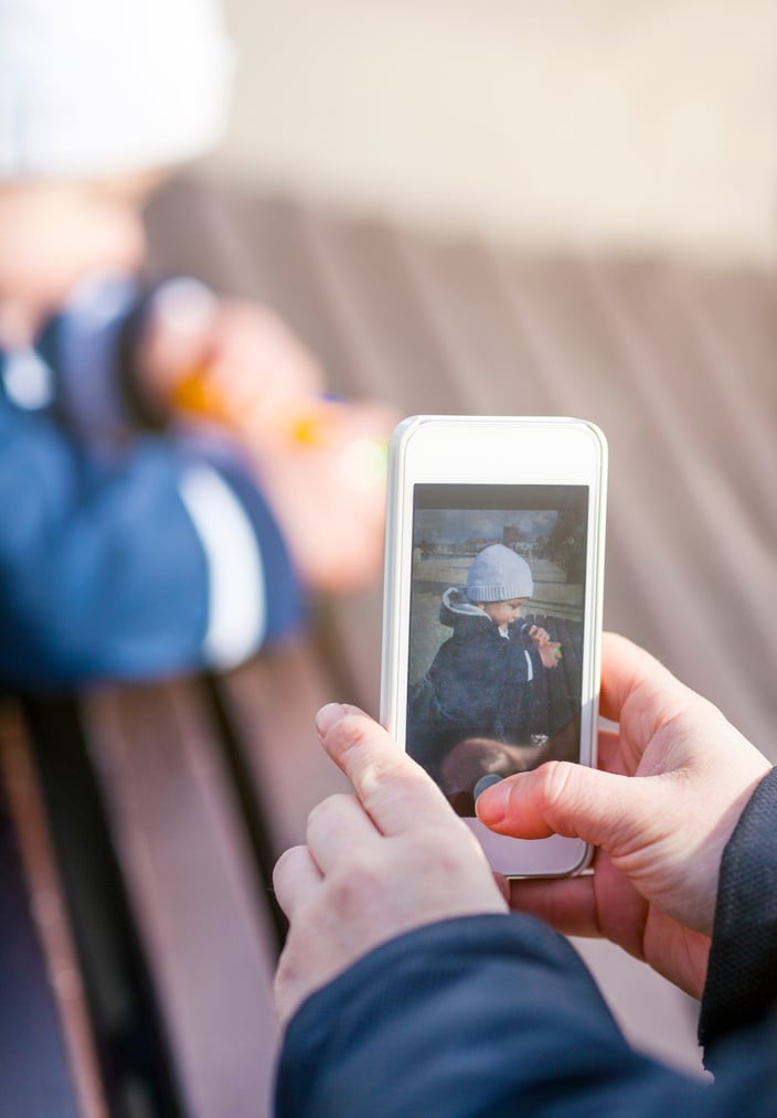 Parent photographing child with smart phone